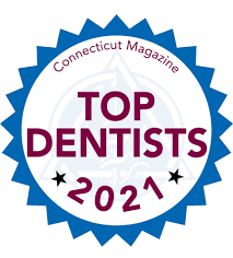 The image features a graphic badge with text elements, including the words 'Top Dentists 2021' prominently displayed at the top. Below this, there's an emblem stating 'Connecticut Magazine' and a circular seal indicating that the magazine is the source of recognition for these dentists. The central part of the badge has a blue background with white text reading 'TOP DENTISTS 2021.' The overall style of the image suggests it is a digital graphic, possibly used to denote an award or recognition given by Connecticut Magazine in 2021.