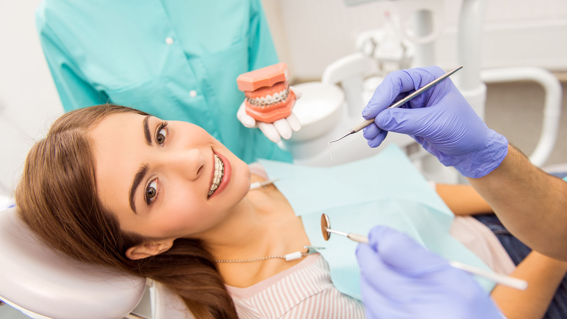 An adult female patient receiving dental care while smiling at the camera.