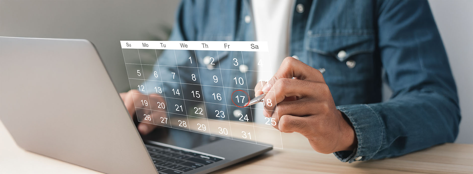 A person working on a laptop with a calendar displayed on the screen.