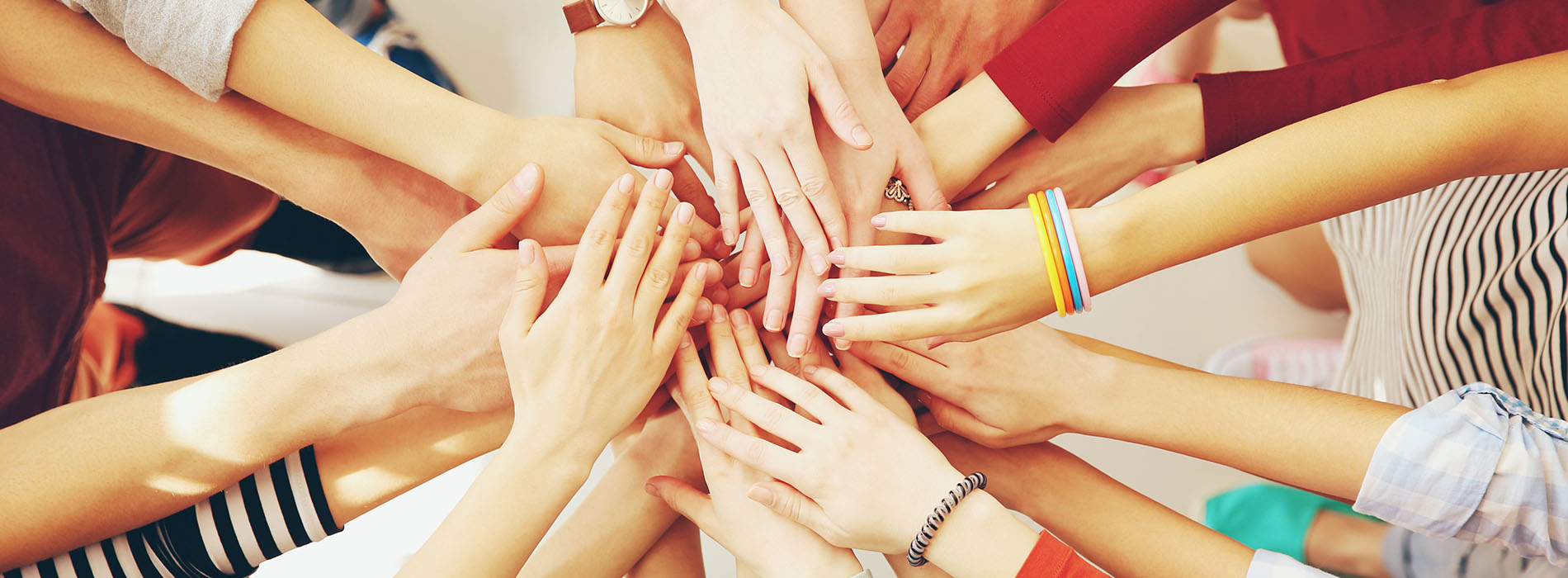 A group of people are standing together, forming a circle with their hands, creating a sense of unity and support.