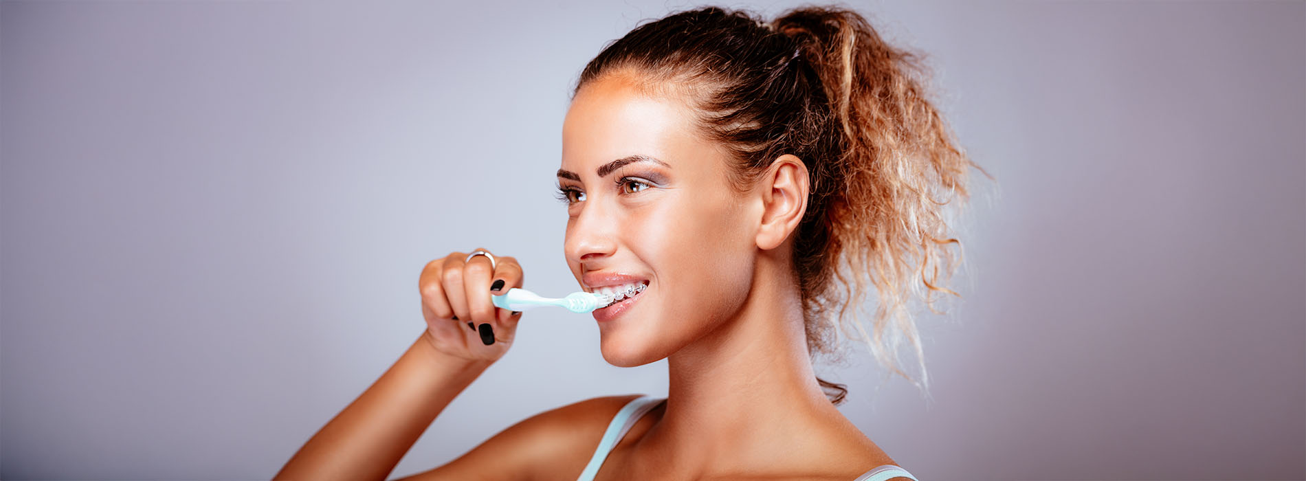 A woman brushing her teeth with a toothbrush.