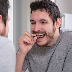 The image shows a man brushing his teeth while looking at another person who appears to be observing him.