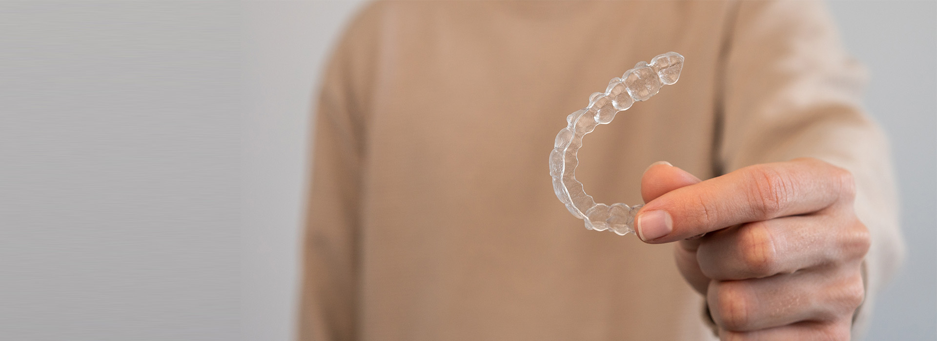 The image shows a person holding a soap bubble with their hand against a light background.