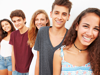 A group of young people smiling at the camera with a white background.